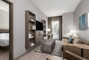 A modern hotel room with a bed, a sofa, a TV, and a desk with a lamp. - AC Hotels by Marriott Charlotte City Center (Charlotte)