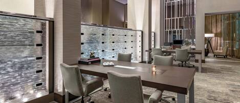 A modern conference room with a long table, several chairs, and a large glass partition.