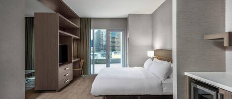 Habitación de hotel moderna con una cama grande, televisión, escritorio y vistas a la ciudad a través de la ventana.