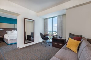 A hotel room with a bed, a desk, a chair, a sofa, and a large window with a view. - Residence Inn by Marriott Charlotte City Center (Charlotte)