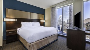 Une chambre d’hôtel avec un grand lit, un bureau, une télévision et une vue sur la ville.