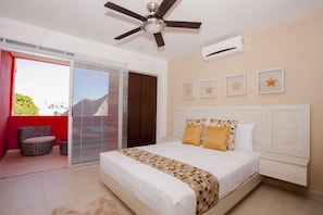 A bedroom with a bed, a ceiling fan, a window with blinds, and a balcony with a chair. - Hotel Isla Zamna (Isla Mujeres)
