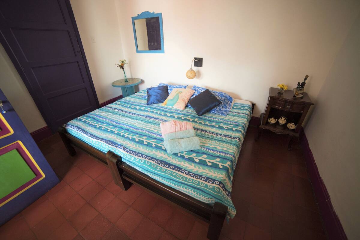 A bedroom with a bed, a dresser, a mirror, and a door.