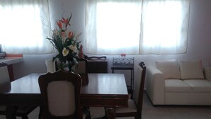 A living room with a dining table, chairs, a sofa, and a decorative plant. - Apartamento en PlayadelCarmen 531 by Sinbad (Playa del Carmen)