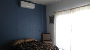 A bedroom with a bed, a chair, a picture on the wall, and a window with curtains. - Apartamento en PlayadelCarmen 531 by Sinbad (Playa del Carmen)