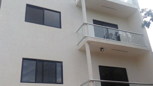 A multi-story building with balconies, large windows, and a visible entrance. - Apartamento en PlayadelCarmen 531 by Sinbad (Playa del Carmen)