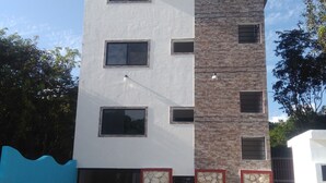 A multi-story building with a white facade and a stone accent wall. - Apartamento en PlayadelCarmen 531 by Sinbad (Playa del Carmen)