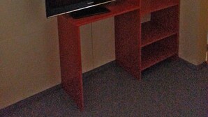 Een rode tv-meubel met een flatscreentelevisie in een kamer met effen muren en een tapijtvloer.