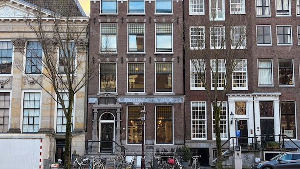 Een rij historische gebouwen met grote ramen en een straat ervoor.