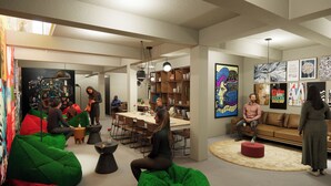 Een modern interieur met groene en rode schapenvachtjes, een eethoek en kunstwerken aan de muren.