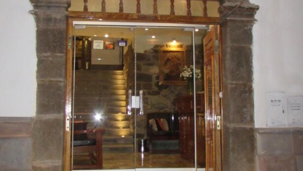 The entrance to ARCANGEI Hotel with a stone facade and a glass door. - Hotel Arcangel (Cusco)