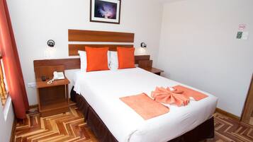 Habitación de hotel con una cama grande, cabecero de madera, dos mesitas de noche, un teléfono y un cuadro en la pared.