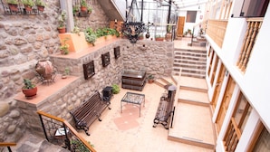A stone-walled courtyard with outdoor seating, a staircase, and potted plants. - Hotel Arcangel (Cusco)