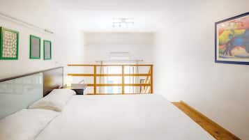Habitación de hotel con cama, escritorio, silla, ventana y obras de arte en las paredes.