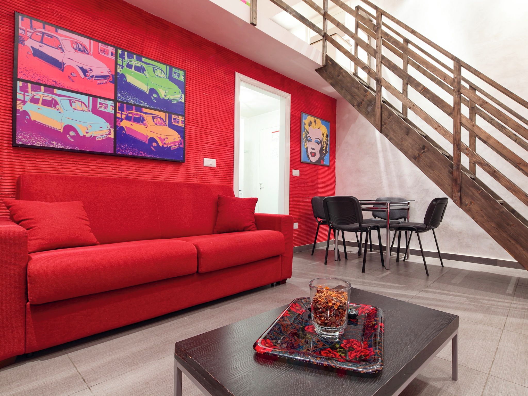 Un soggiorno moderno con un divano rosso, un tavolino da caffè con un vassoio decorativo e una scala.