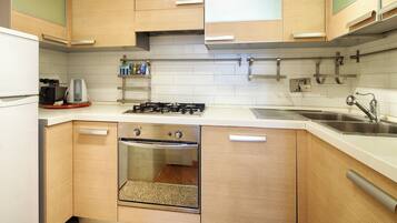 Una cucina compatta con mobili in legno, forno integrato, piano cottura a gas e lavello in acciaio inossidabile.