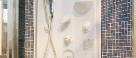 A white bathtub with a handheld showerhead and control knobs.