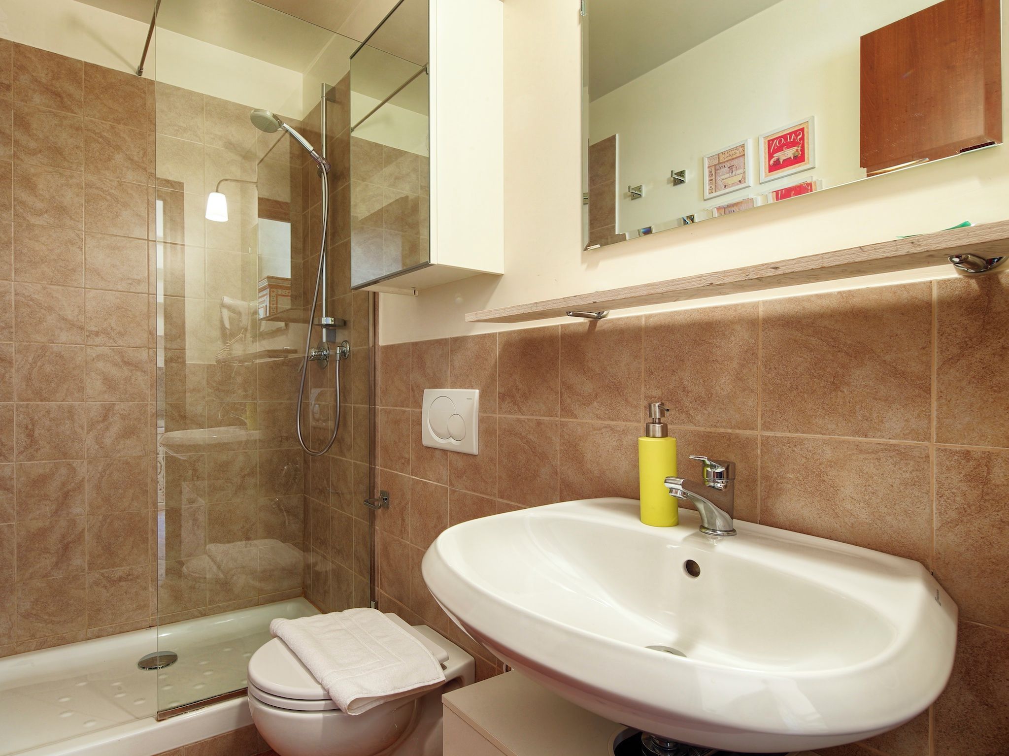 Un bagno con doccia, toilette, lavabo e uno specchio sopra il lavabo.