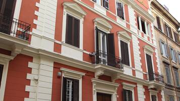 Un immeuble à plusieurs étages doté de balcons, d’une porte et d’une fenêtre avec des volets.
