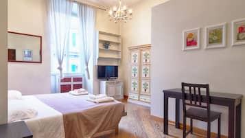 Une chambre d’hôtel équipée d’un lit, d’un bureau, d’une chaise, d’une télévision et d’un lustre.