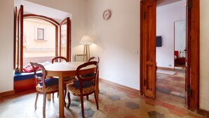 Un comedor con mesa y sillas de madera, una lámpara y un reloj en la pared.