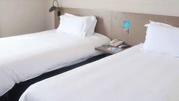 A hotel room with two single beds, a nightstand, a lamp, and a framed picture on the wall. - Jinjiang Inn Select Dalian Youhao Square (Dalian)
