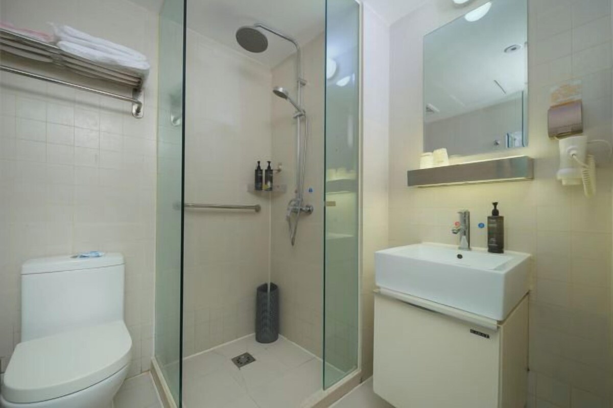 A modern bathroom with a glass-enclosed shower, a white sink, and a toilet.