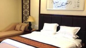 A hotel room with a bed, a sofa, a nightstand, and a decorative wall panel. - Hanyun Huidu Hotel (Huaibei)