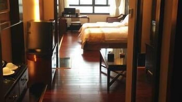 A hotel room with a bed, a desk, a chair, a television, and a window. - Hanyun Huidu Hotel (Huaibei)