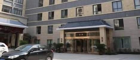 A multi-story hotel with a modern design, featuring a central entrance with glass doors and a flat roof.
