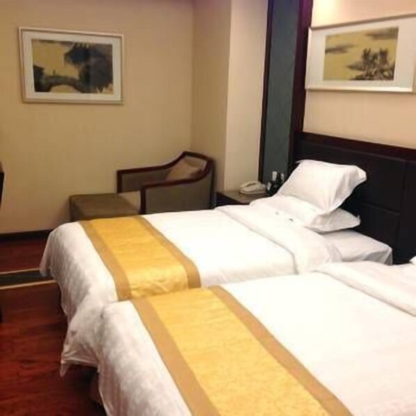 A hotel room with two beds, a nightstand, a chair, and two framed pictures on the wall. - Hanyun Huidu Hotel (Huaibei)