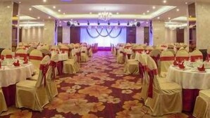 A banquet hall with round tables, chairs, and a floral carpet. - Yuyuanhotel (Zhangzhou)