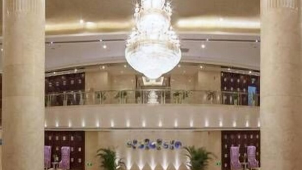 A grand lobby with a chandelier, marble columns, and a central round table with a floral arrangement. - Yuyuanhotel (Zhangzhou)
