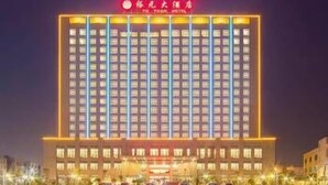A multi-story hotel with a uniform facade, illuminated windows, and a prominent entrance with signage. - Yuyuanhotel (Zhangzhou)