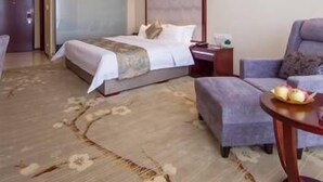 A hotel room with a bed, a chair, a small table with fruit, and a painting on the wall. - Yuyuanhotel (Zhangzhou)