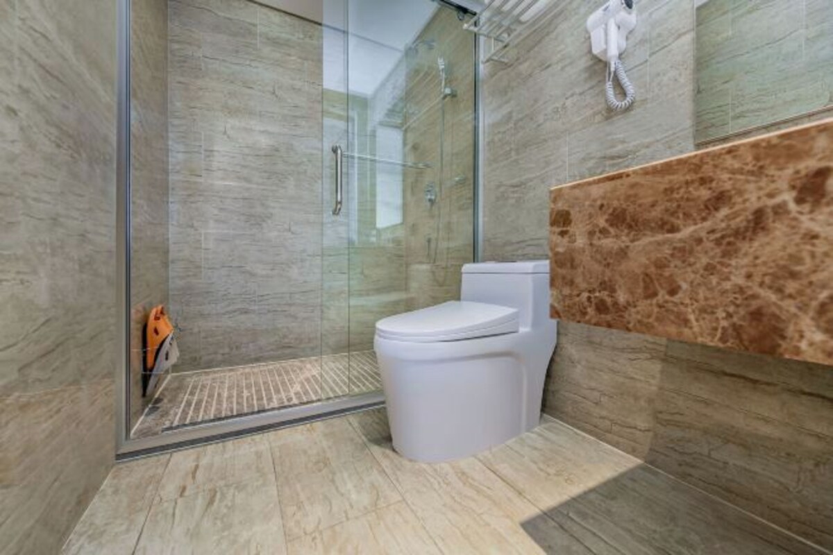 A modern bathroom with a glass-enclosed shower, a white toilet, and a marble backsplash.