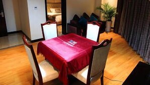 En spiseplads med et bord dækket til fire personer, en loftlampe og en potteplante.