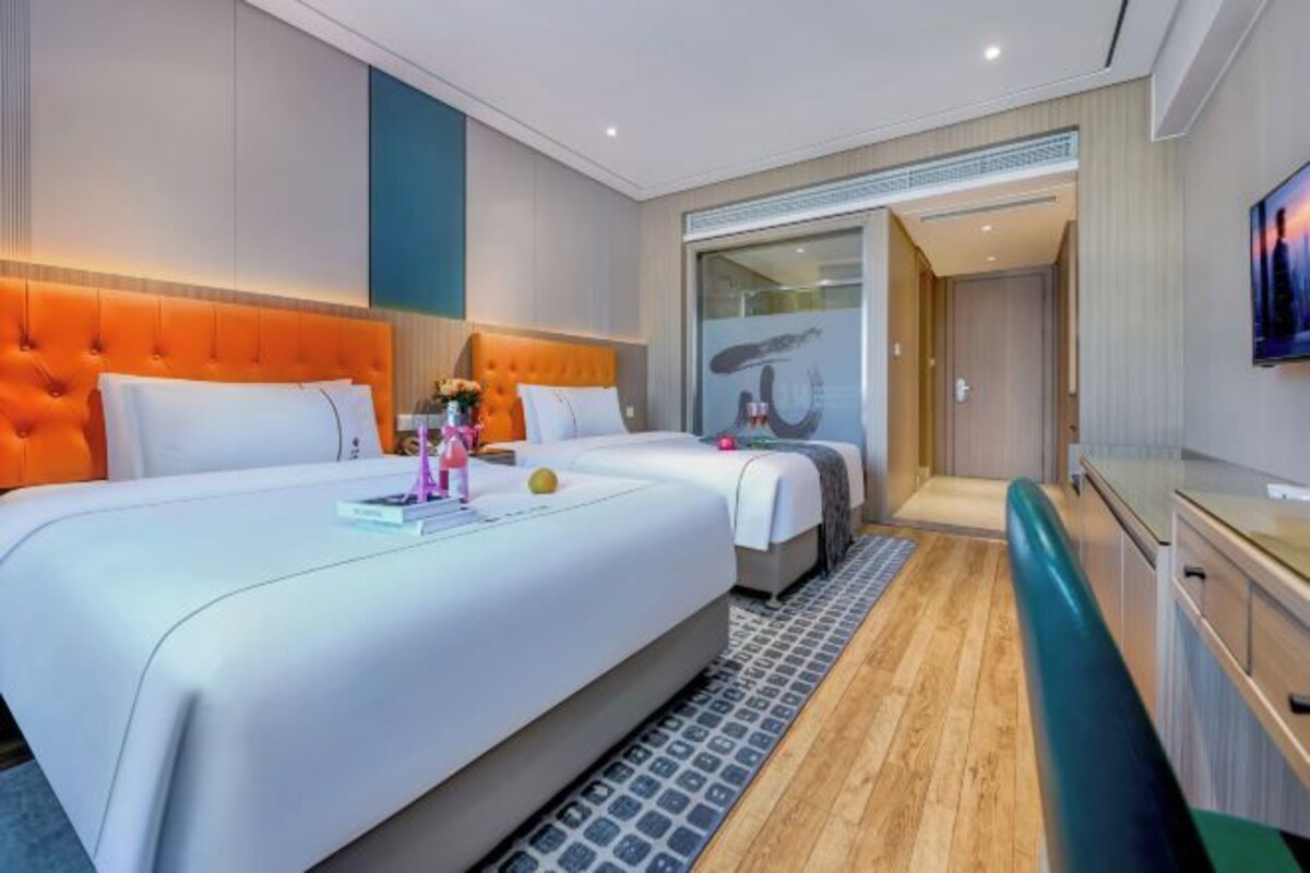A hotel room with a large bed, a smaller bed, a desk, and a TV.