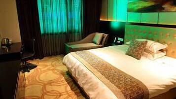A hotel room with a large bed, a desk, and a chair.