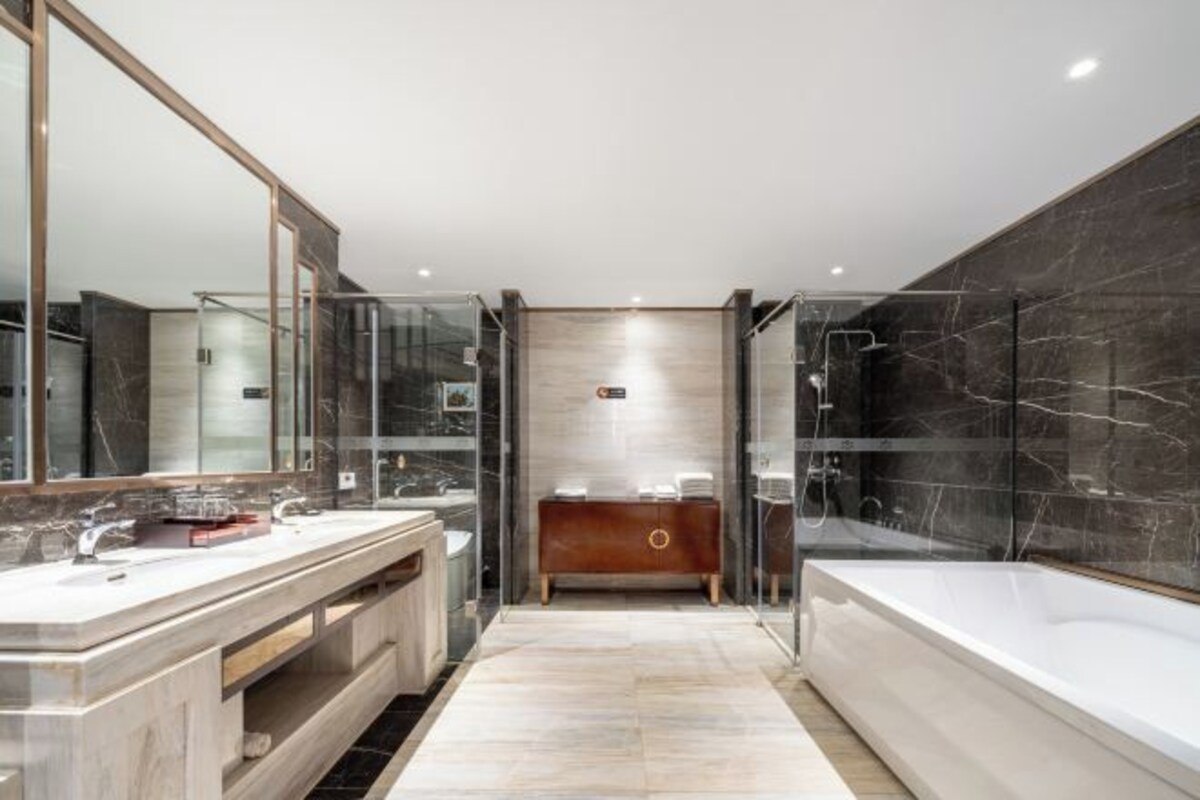Une salle de bain moderne avec un grand miroir, deux lavabos, un meuble-lavabo et une baignoire.