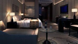 Une chambre d’hôtel moderne équipée d’un lit, d’un canapé, d’une petite table et d’un téléviseur.