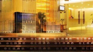 A hotel entrance with a reception desk, a large logo above the entrance, and a series of windows with vertical blinds. - Shenzhen Shangpin Hotel (Shenzhen)