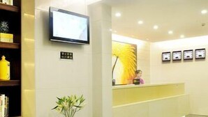 A reception area with a sofa, a small table with a vase, a TV, and framed pictures on the wall. - Shenzhen Shangpin Hotel (Shenzhen)