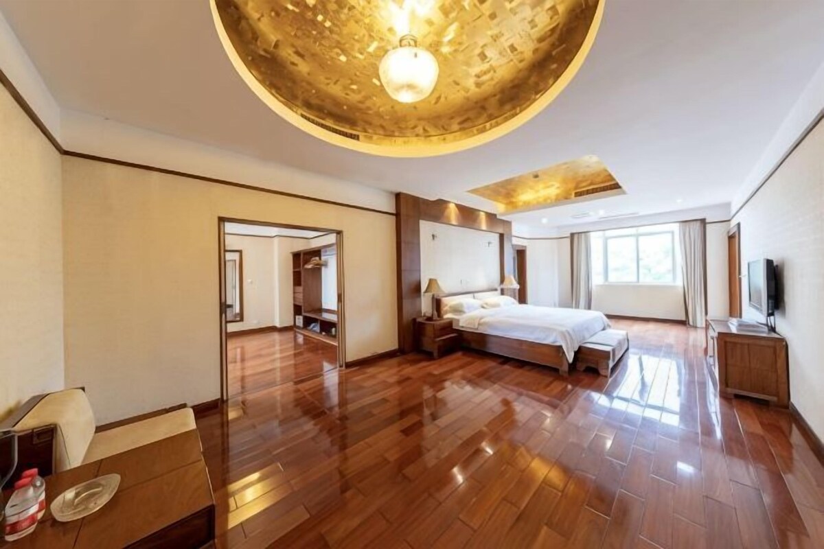 A spacious hotel room with a large bed, a desk, and a TV.