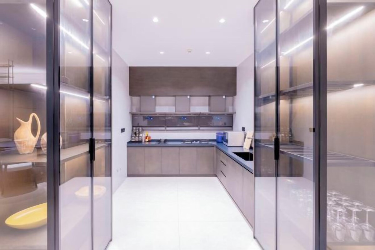 A modern kitchen with glass-fronted cabinets, a central island, and a built-in oven.