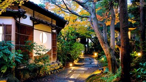 A traditional Japanese building with a stone pathway leading through a forested area. - Heihachi Tea House Inn (Kyoto)