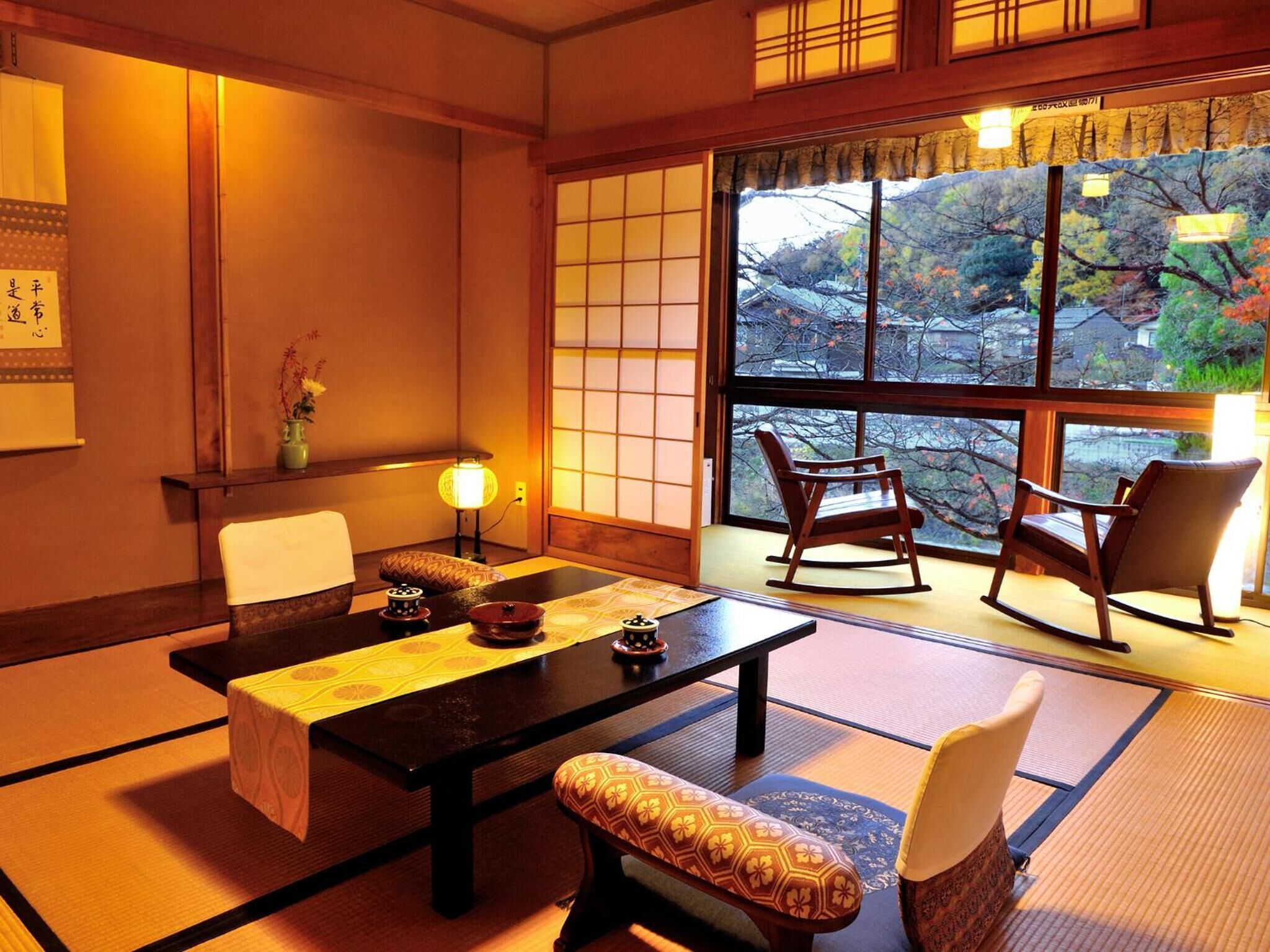 Une pièce de style japonais traditionnel, avec un sol recouvert de tatamis, une table basse et deux fauteuils à bascule.