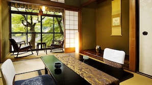 A traditional Japanese room with tatami flooring, a low table with a tea set, and a view of trees through a shoji screen. - Heihachi Tea House Inn (Kyoto)