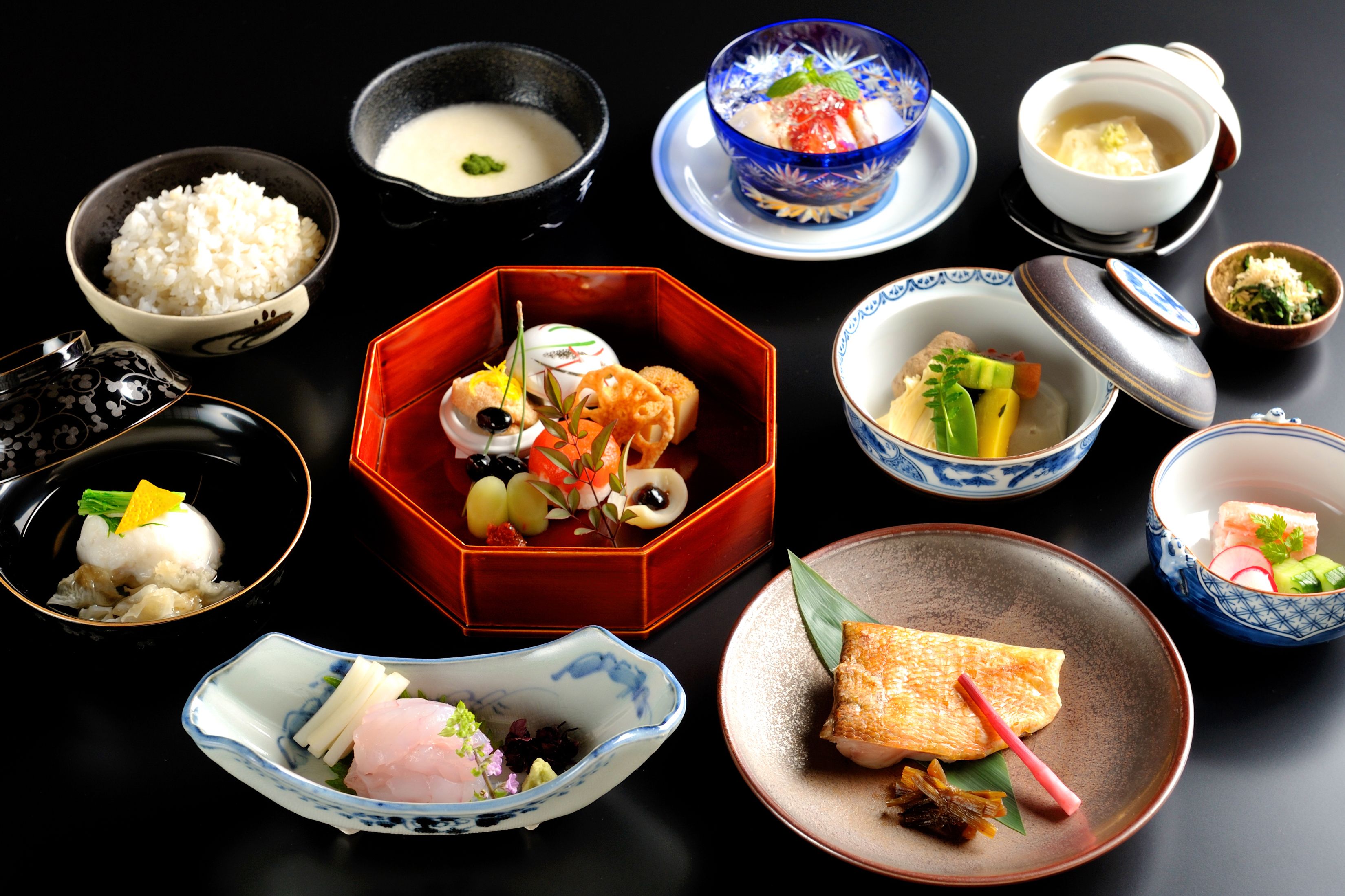 A variety of Japanese dishes arranged on a table, including rice, soup, and seafood.