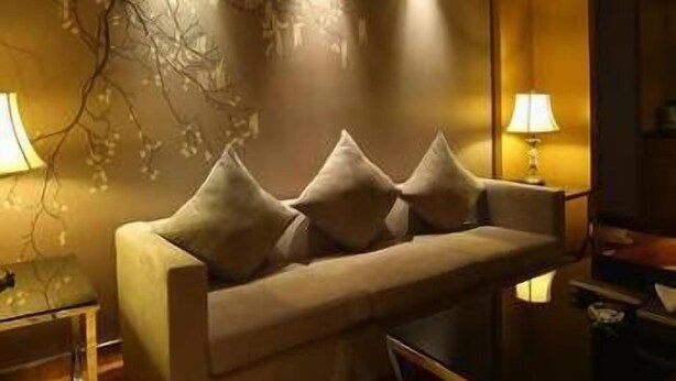 A modern living room with a sofa, two lamps, and a decorative wall piece. - Beautiful Landscape Hotel (Liangshan Yi)